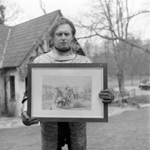 Adrian holding a framed illustration of the joust between the Knight of the Red Rose and the Lord of the tournament, by Thomas Hodgson (march 1948).